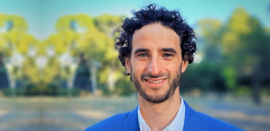 Riccardo Beltramo, smiling, in blue suit against blurred background of trees