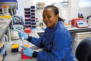 woman wearing blue lab coat with pipette