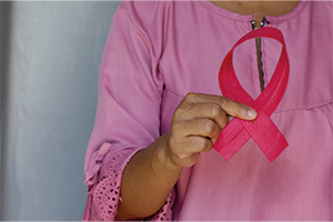 Woman holds pink breast cancer awareness ribbon. Credit angiola-harry-unsplash