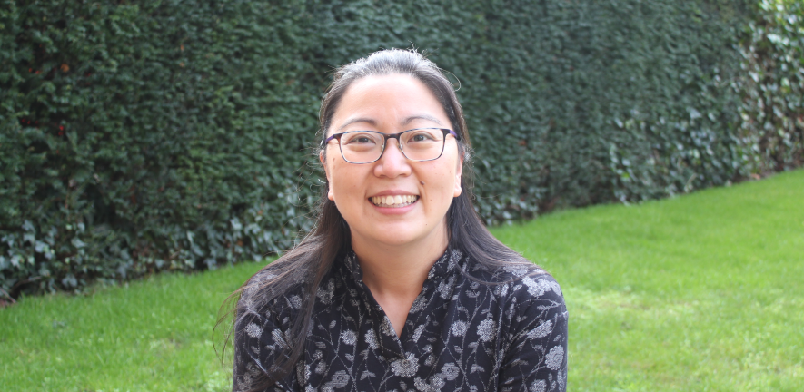 Head and shoulder shots of Janet Kumita in a black shirt, smiling, standing on a lawn with a hedge in the background