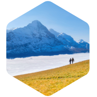 two people walking in yellow hill with snowy mountains in the background