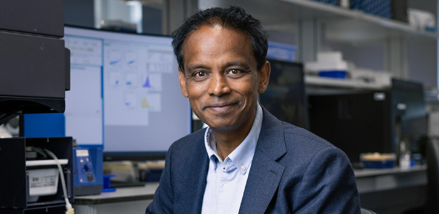 James Thaventhiran, in a blue blazer, sitting in a computer lab
