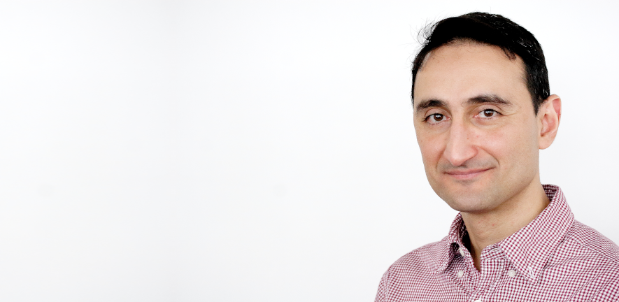 Ashraf Zarkan, smiling, in a checked shirt on a white background