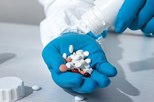 Antibiotics. Credit: AVAKAphoto person wearing blue gloves pouring tablets onto their hand. Credit: AVAKAphoto