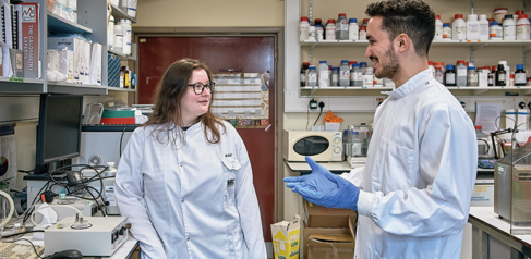 two scientists wearing lab coats in the lab talking