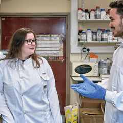two scientists wearing lab coats in the lab talking