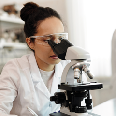 woman in lab looking through microscope