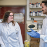 two scientists wearing lab coats in the lab talking