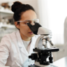 woman in lab looking through microscope