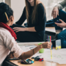 people sitting around table with paper and pens