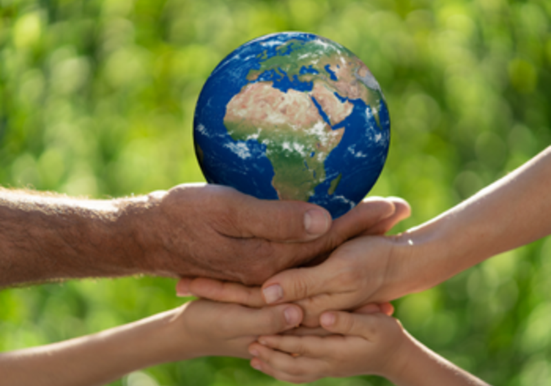 hands holding a planet on a green bakground