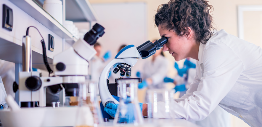 woman wearing a lab coat looking into a microscope