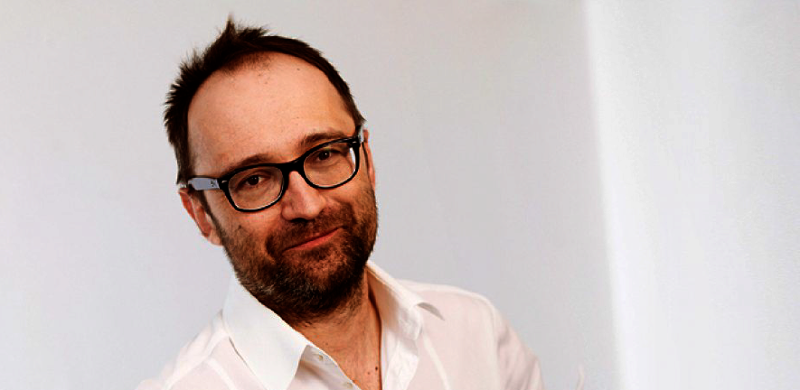 Head and shoulders shot of David Keays, wearing white shirt and glasses, with a beard, against a white background